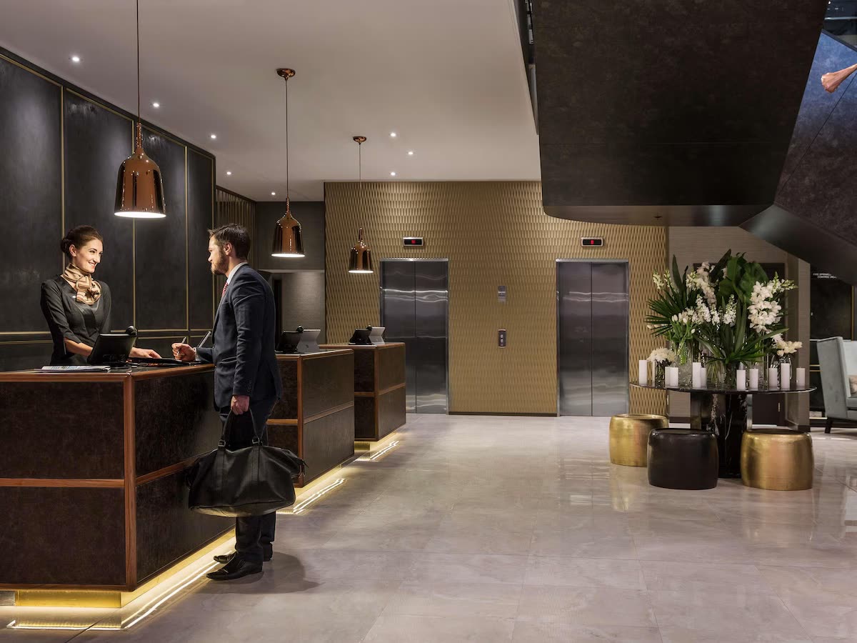 A hotel lobby with a front-desk team welcoming arriving guests